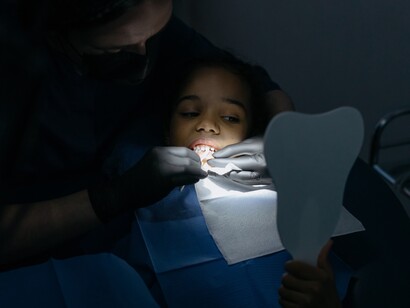 Dentist flashes light for dental examination on young girl