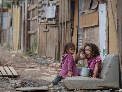 Two children in the favelas of Brazil, eating out of a pot