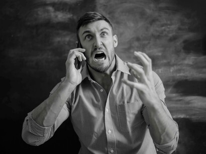 A man allowing his stress to managing his behavior as he yells angrily into the phone