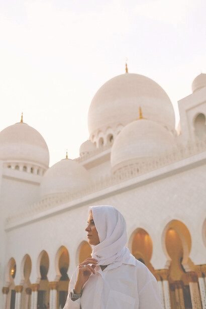 Beneath the Abu Dhabi sun, a woman in a hijab graces the Grand Mosque North Parking Lot in the United Arab Emirates with her presence