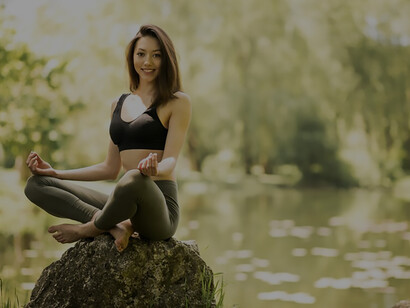 In nature's embrace, a woman finds serenity, practicing yoga on a forest rock
