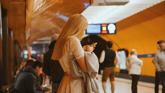 A woman focused on her smartphone in a busy transit hub, highlighting the need for secure identity verification in an increasingly connected world