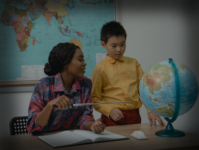 A female teacher discusses the world globe with a young male student