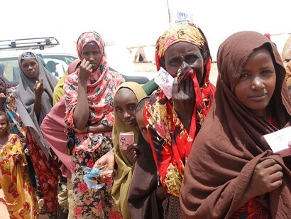 Las mujeres hacen fila sosteniendo sus tarjetas de comida afuera de un centro de alimentación en el campo de tránsito de Dollo Ado, 2011, frontera con Etiopía
