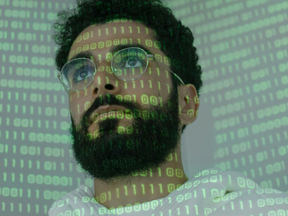 Rostro y paredes reflejan código binario. Cualquier persona puede crear deepfakes con solo una computadora y algo de tiempo libre