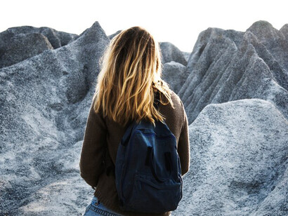 A woman confidently hikes toward the mountain summit, surrounded by the beauty of nature