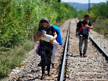 Refugiados sirios caminan por las vías del tren