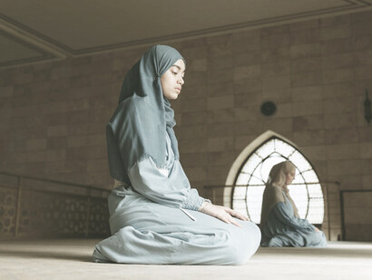 A woman in blue hijab praying