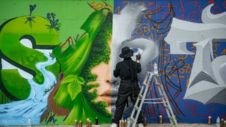 An artist creating graffiti on a wall