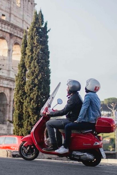 A couple riding a Vespa by the Roman Colosseum