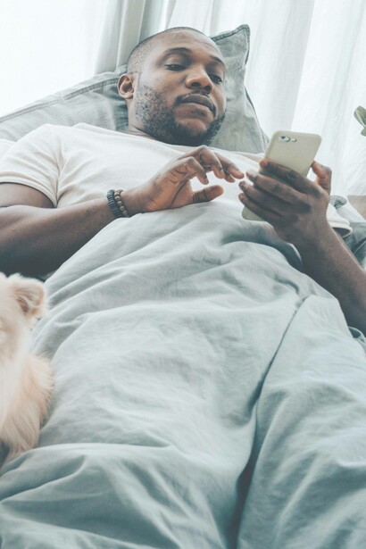 Man lays in bed using phone