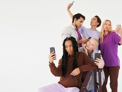 A group of people sitting together but engrossed in their phones, symbolizing the connection and disconnection of social media