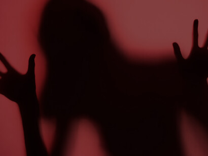 A woman's hands silhouettes emerge from a chilling red shadow