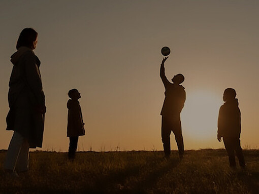 A picturesque scene unfolds as a full-shot silhouette encapsulates a family's radiant joy, playfully engaged, against the breathtaking canvas of a sunset