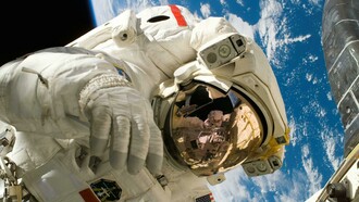 An American astronaut working outside the International Space Station, highlighting the exterior structure and the presence of ISS astronauts in orbit