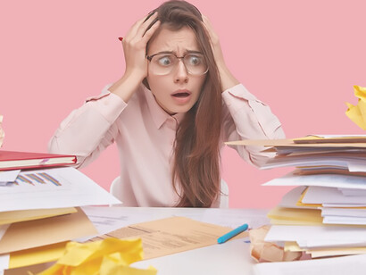 Amidst a sea of books, a young brunette student confronts the challenges of information overload and the data deluge at her desk