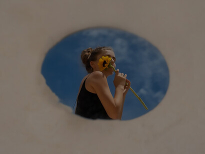Reflecting self-reflection, personal growth, and inner peace, a woman gracefully poses with a round mirror and flower, encapsulating tranquility