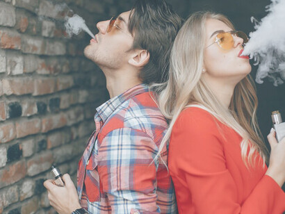 Young couple using an electronic cigarette, both vaping together
