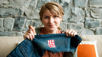 Woman repairing a pair of jeans using traditional visible mending techniques