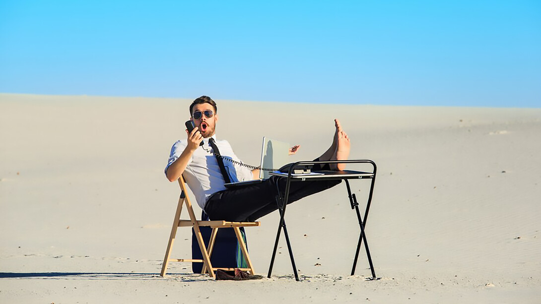 Businessman working on a laptop in a desert, highlighting flexible work arrangements and summer productivity