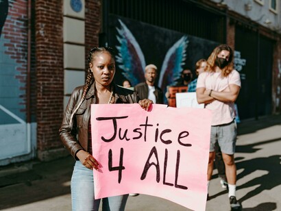 A group a young people on the street with a sign