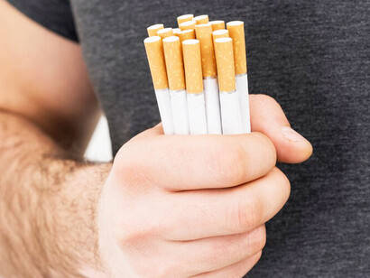 A man holding a bundle of cigarettes in his hand