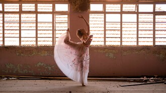 Uma bailarina encontra, entre a luz e as marcas do tempo, a delicadeza de um gesto suspenso. Há movimentos que o corpo aprende, mas há outros que parecem nascer de um fogo interior que o tempo não consegue apagar. Sob a luz que atravessa o antigo espaço, a bailarina transforma o próprio corpo em gesto e presença. Como na vida, a dança não interrompe o tempo: encontra novas formas de continuar
