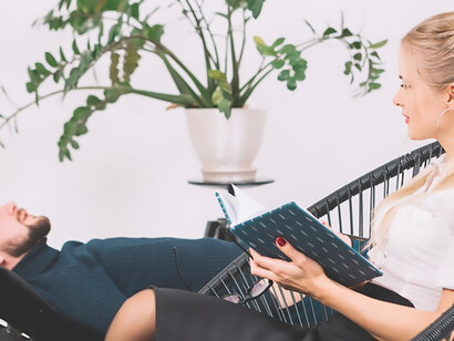 Explore the therapeutic journey as a female psychologist diligently takes notes in her diary while a patient rests on a couch in the clinic, fostering a supportive environment for mental health