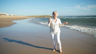 Mulher desfruta de música enquanto caminha na praia. Não importa onde você está. Não importa o que já viveu ou deixou de viver. Sempre há espaço para um novo capítulo. Pense nos anos que já passaram. Quantas vezes você se reinventou sem perceber? Talvez tenha mudado de emprego, de cidade, de relacionamento, de direção. A vida é feita de recomeços, mesmo que a gente não os chame assim