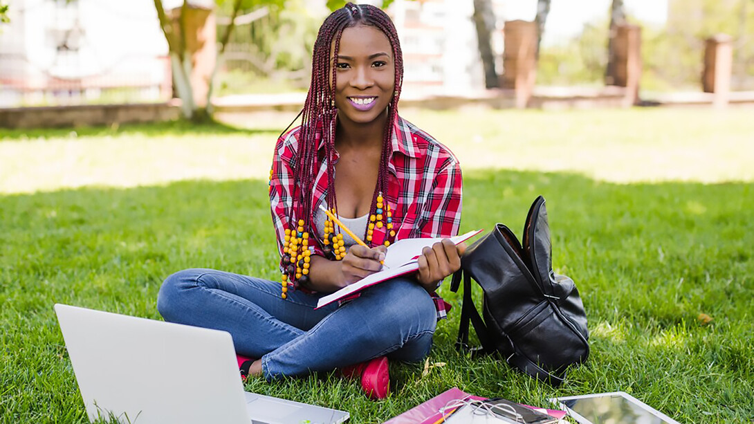 International student studying outdoors, posing in a scenic park