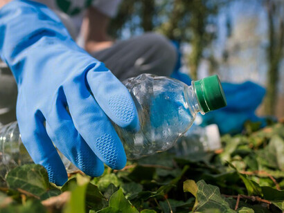 An environmentally-conscious man gathers plastic debris in a littered park, emphasizing the critical importance of bioplastics, sustainable products, and comprehensive recycling initiatives
