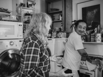 A volunteer helps an elderly man do chores in his kitchen
