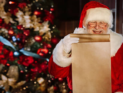 A joyful Santa Claus poses beside a festive Christmas tree, carefully reviewing a scroll brimming with holiday wishes