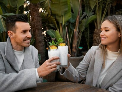 A couple on their first date sips pina coladas at a café, casually scrolling through a dating app