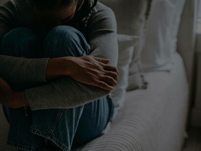 A woman with her head between her legs and cradling as she faces the aftermath of a difficult situation