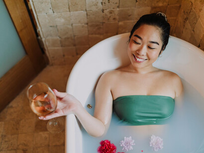 A woman relaxing on a bathtub and drinking wine