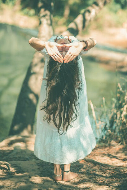 A woman gracefully embodies the Ayurvedic lifestyle as she leans and finds peace under the sheltering embrace of a tree