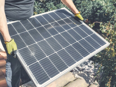 A man is in the process of mounting solar panels onto his residence to capture solar energy