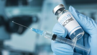 A person holding a COVID-19 vaccine syringe, representing the global struggle between prevention and panic