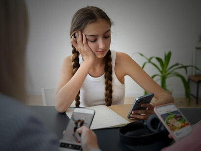A young woman holding a smartphone, looking visibly upset, reflecting feelings of depression and loneliness caused by online comparison and the impact of social media on self-esteem