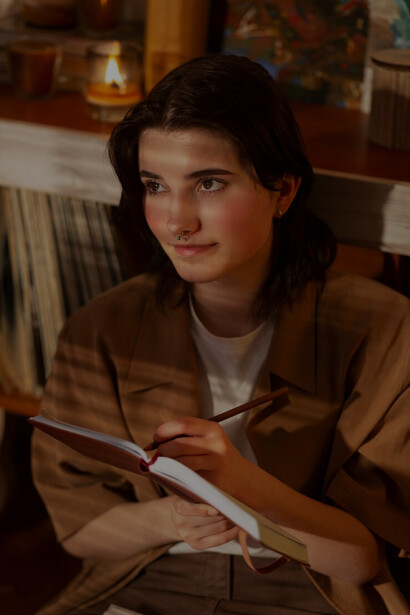 A woman journaling at home explores the balance between creative freedom and ethical storytelling within the publishing industry, addressing cultural sensitivity and writing morality
