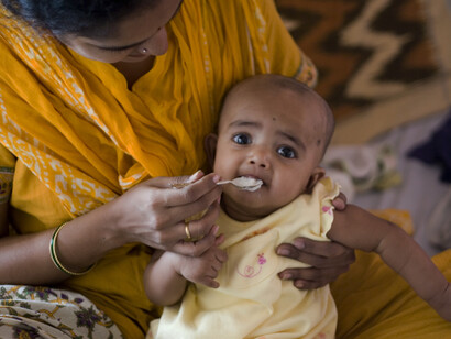 Annaprasana, getting the first solid food (cereals), one of the Hindu-Samskara or Sanskar (consecration). Baby girl getting her first spoon-ful of rice from a custom made silver spoon, India