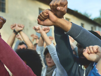 A close-up shot captures a throng of protesters on the streets, their arms raised in collective demonstration