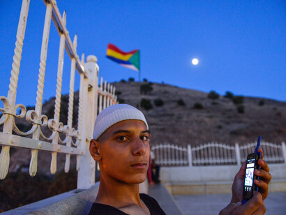 A young man sits outside Jethro's Tomb, with the Druze flag flying behind him. Photo Aviram Valdman