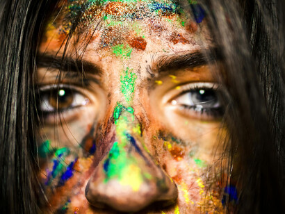 Close-up of a woman's face, staring intensely into the camera, smeared with paint