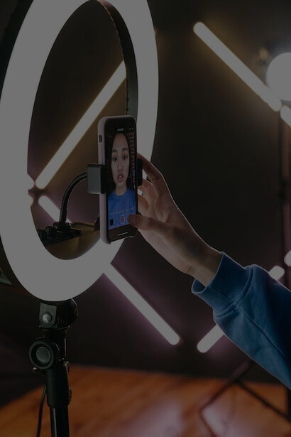 An influencer shooting a video using her smartphone and professional lighting setup