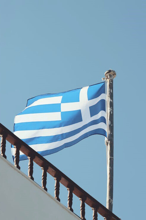 The vibrant Greek flag waves proudly under the bright sunshine in Naxos, Greece