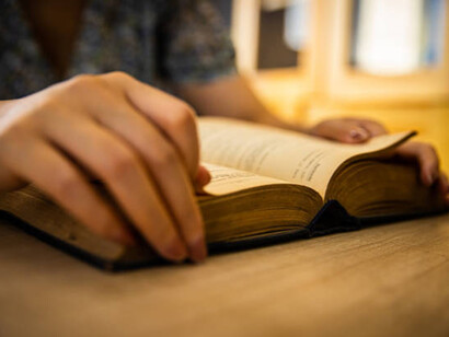 Woman reading and turning the page of an old novel