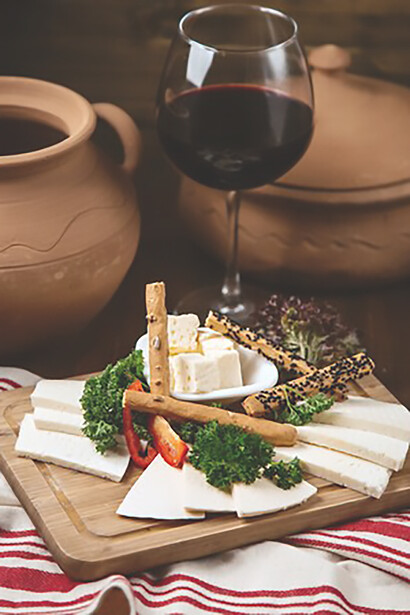 Delectable cheese plate accompanied by a glass of red wine, featuring Pecorino Romano cheese and savory Guanciale, presented in a captivating front view