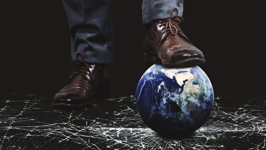 Person stepping on Earth globe with feet concept